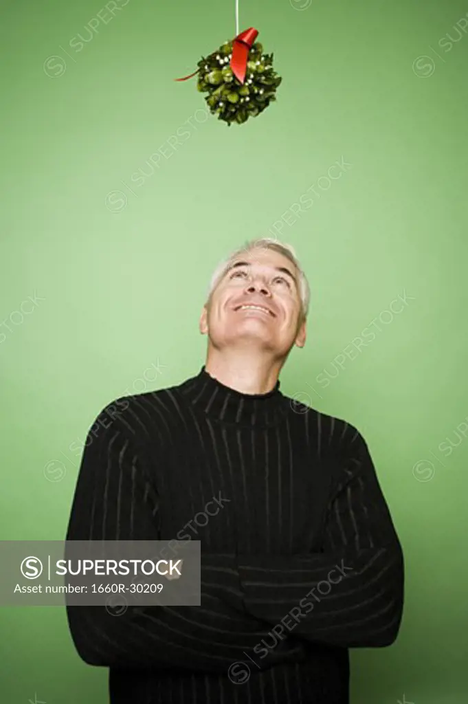 Man with crossed arms under mistletoe at Christmas