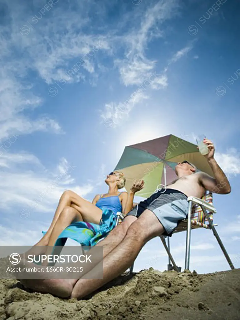 Mature couple at the beach relaxing on deck chairs