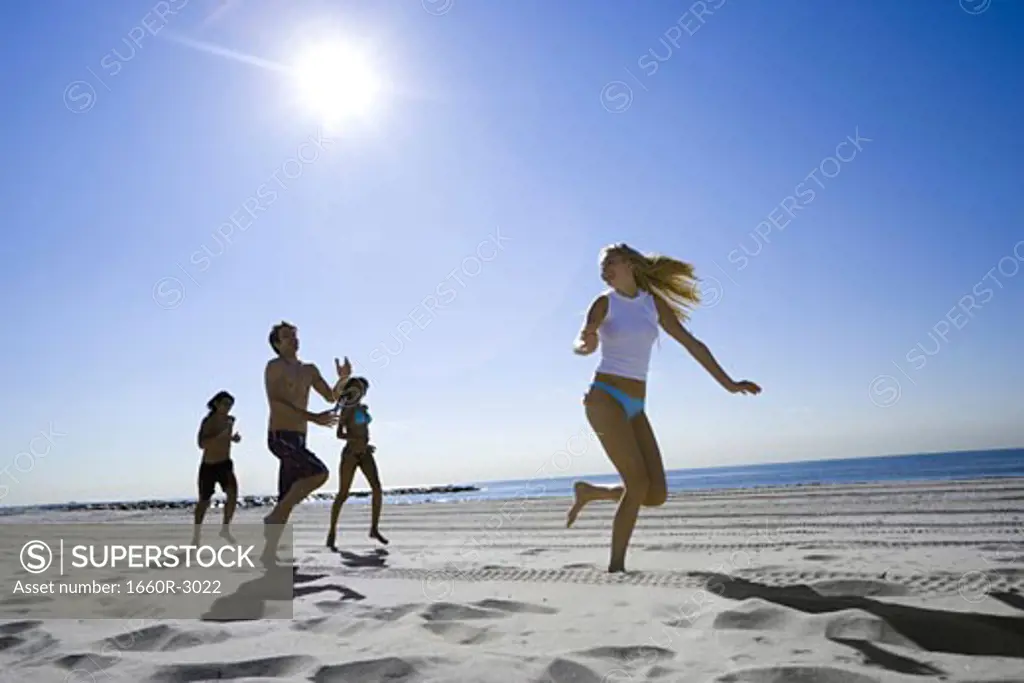 Low angle view of four young people running on the beach