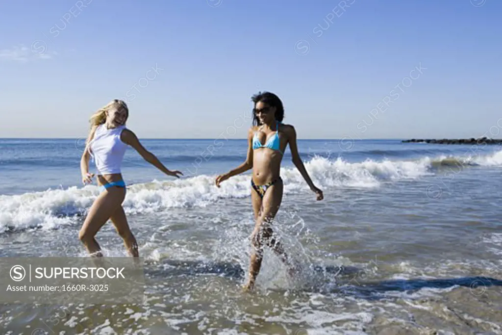 Two young women running in the water on the beach