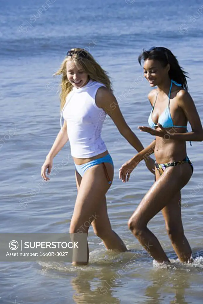 Two young women wading in the water on the beach