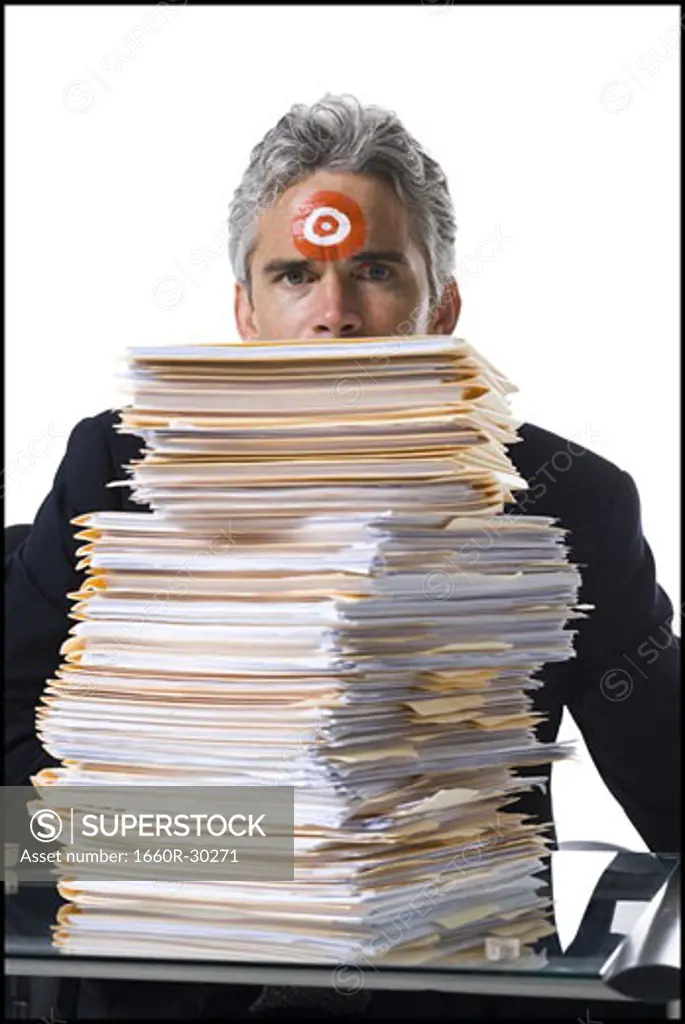 Man with bull's-eye on forehead with stack of papers