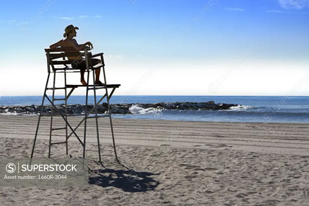 Low angle view of a young man sitting on a lifeguard chair
