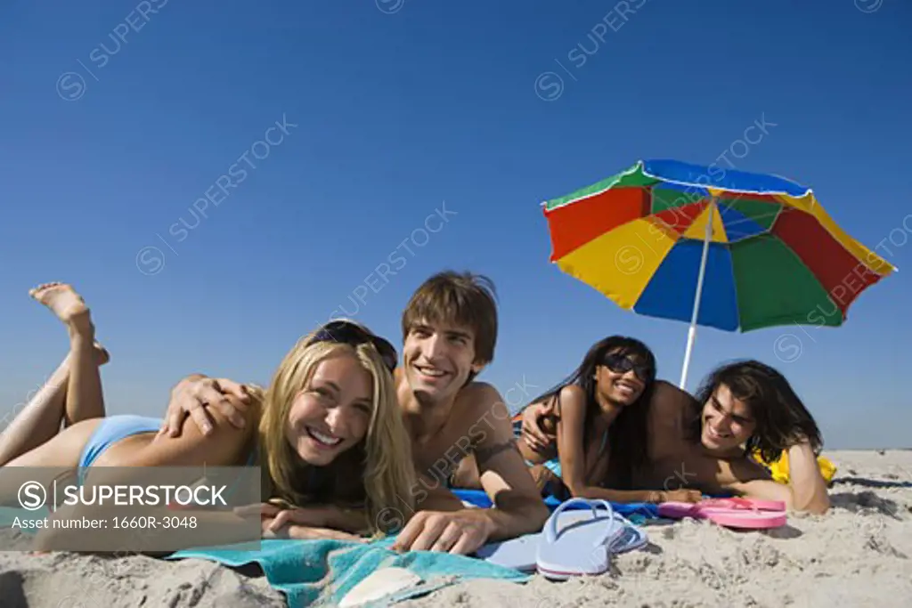 Portrait of four young people lying on the beach