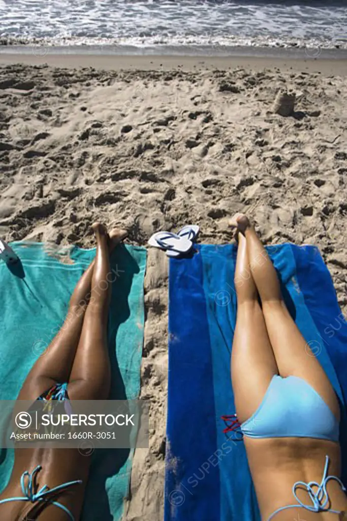 Rear view of two young women sunbathing on the beach