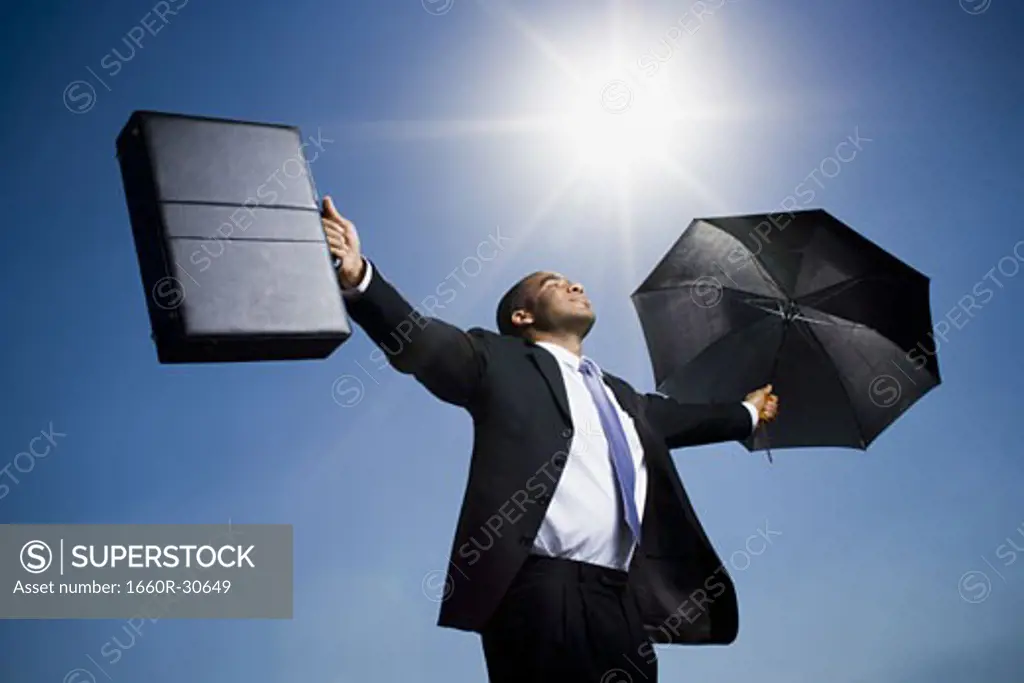 Businessman holding umbrella on a clear day