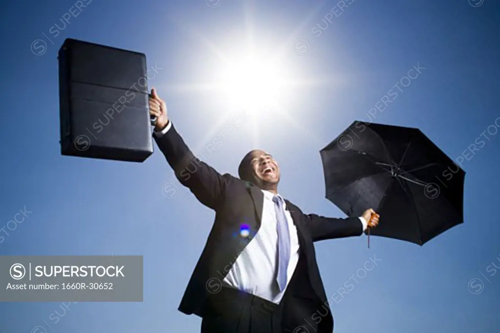 Businessman holding umbrella on a clear day