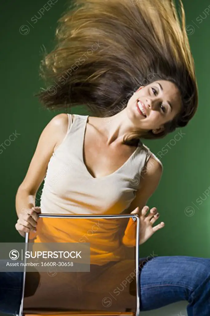 Woman sitting backwards on chair and tossing hair