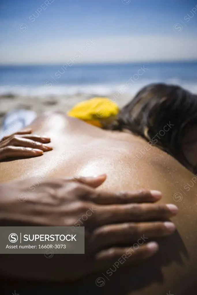 Close-up of a woman's hands massaging a young man's back