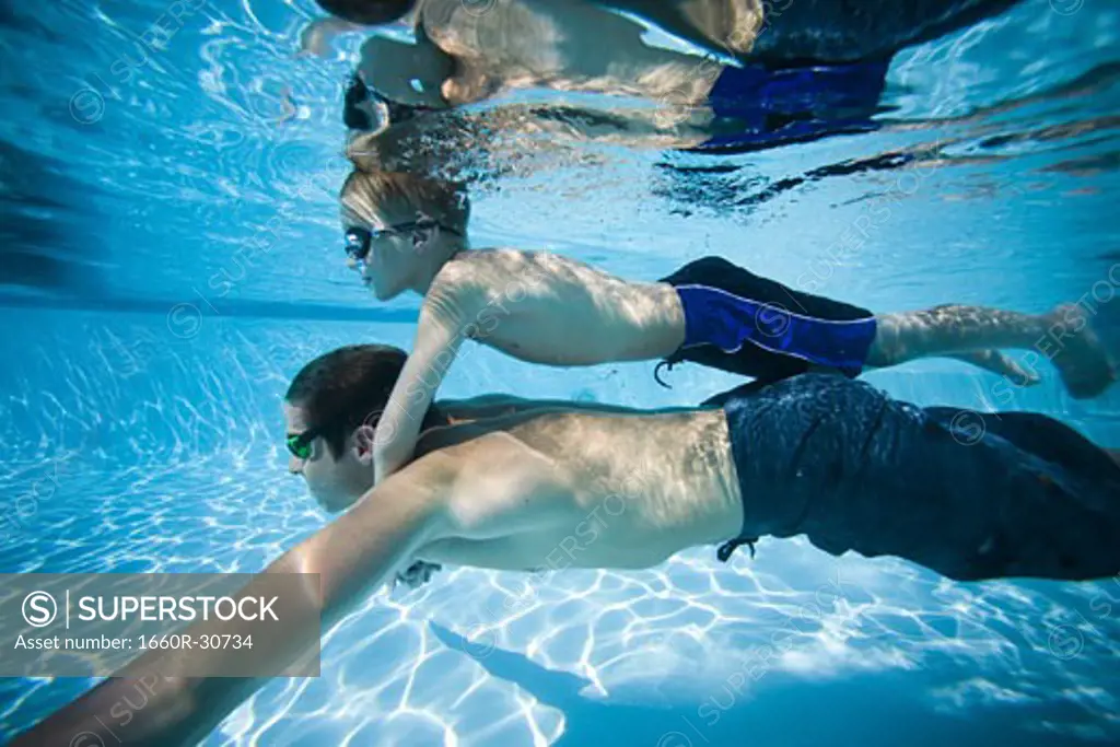 Father and son swimming underwater in pool