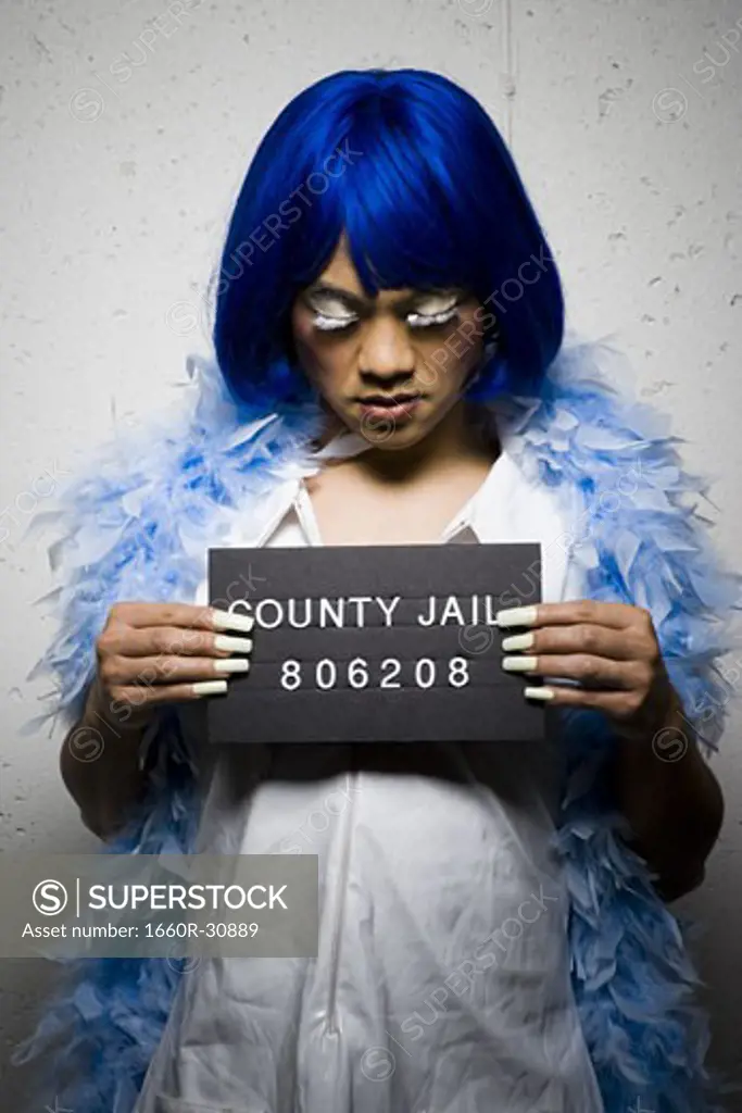 Mug shot of man in drag with blue wig and feather boa