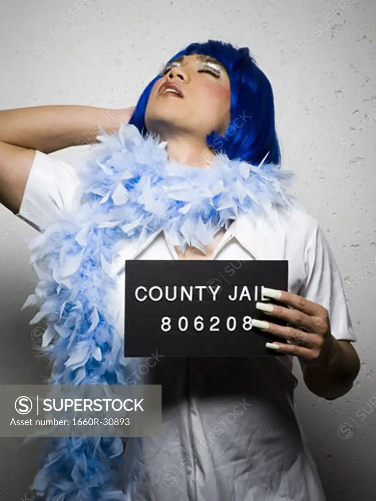 Mug shot of man in drag with blue wig and feather boa
