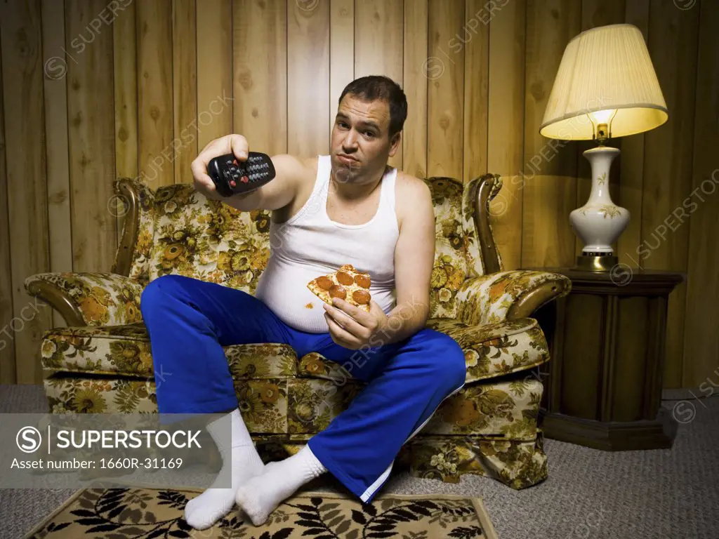 Man on sofa with pizza and TV remote