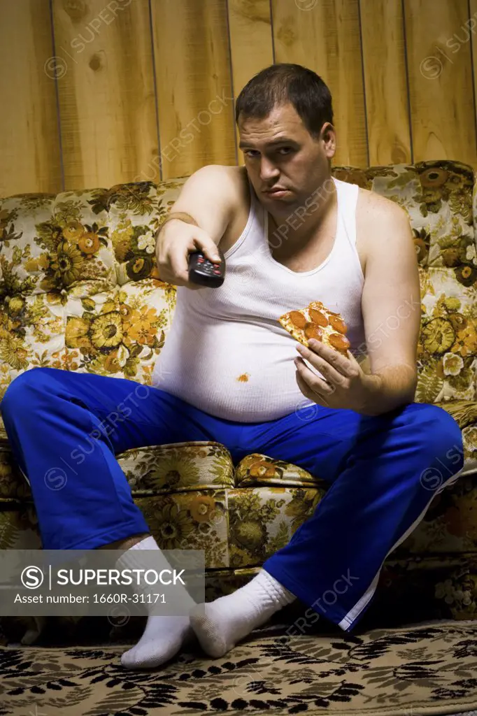 Man on sofa with pizza and TV remote smiling
