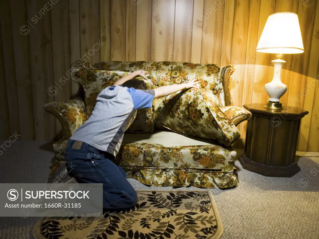 Boy searching under sofa cushions