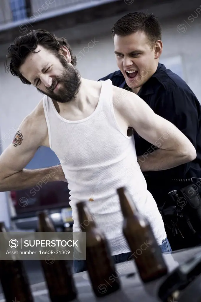 Police officer arresting man lying down with beer bottles