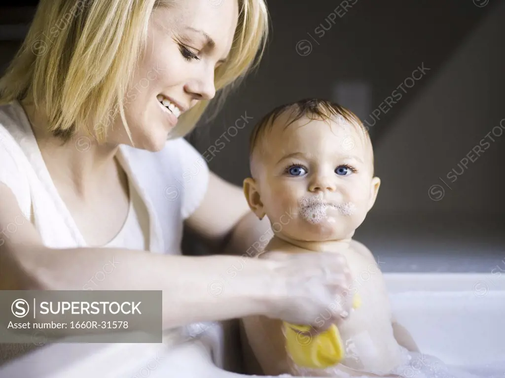 Woman bathing baby in sink