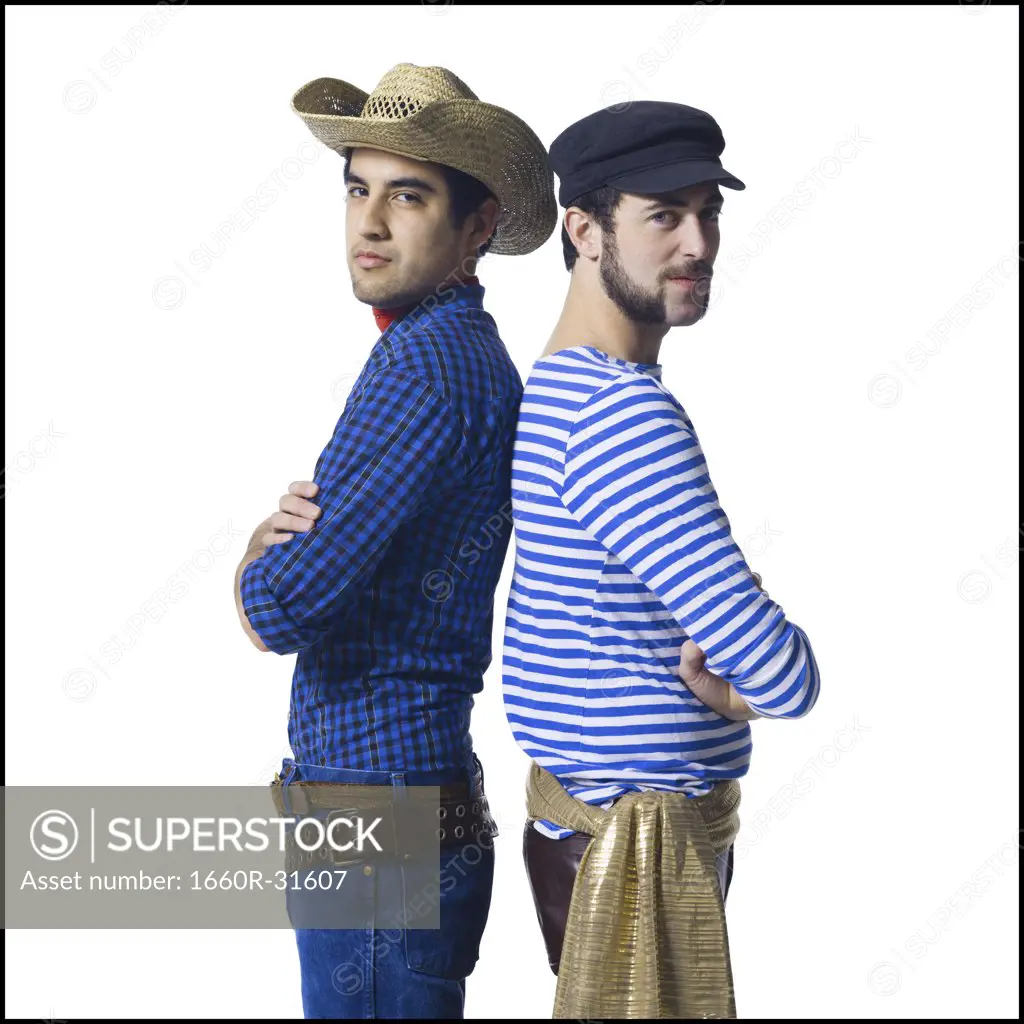 Man in cowboy costume and man in leather pants with waist sash standing back to back