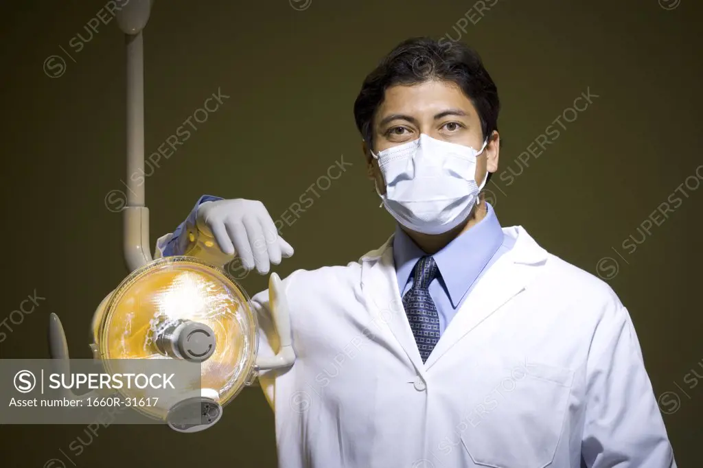 Male doctor or dentist with surgical lamp smiling