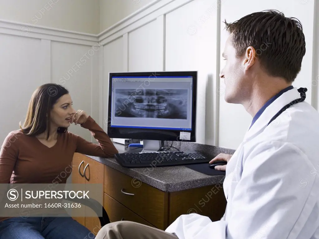 Male doctor or dentist looking at x-rays with woman