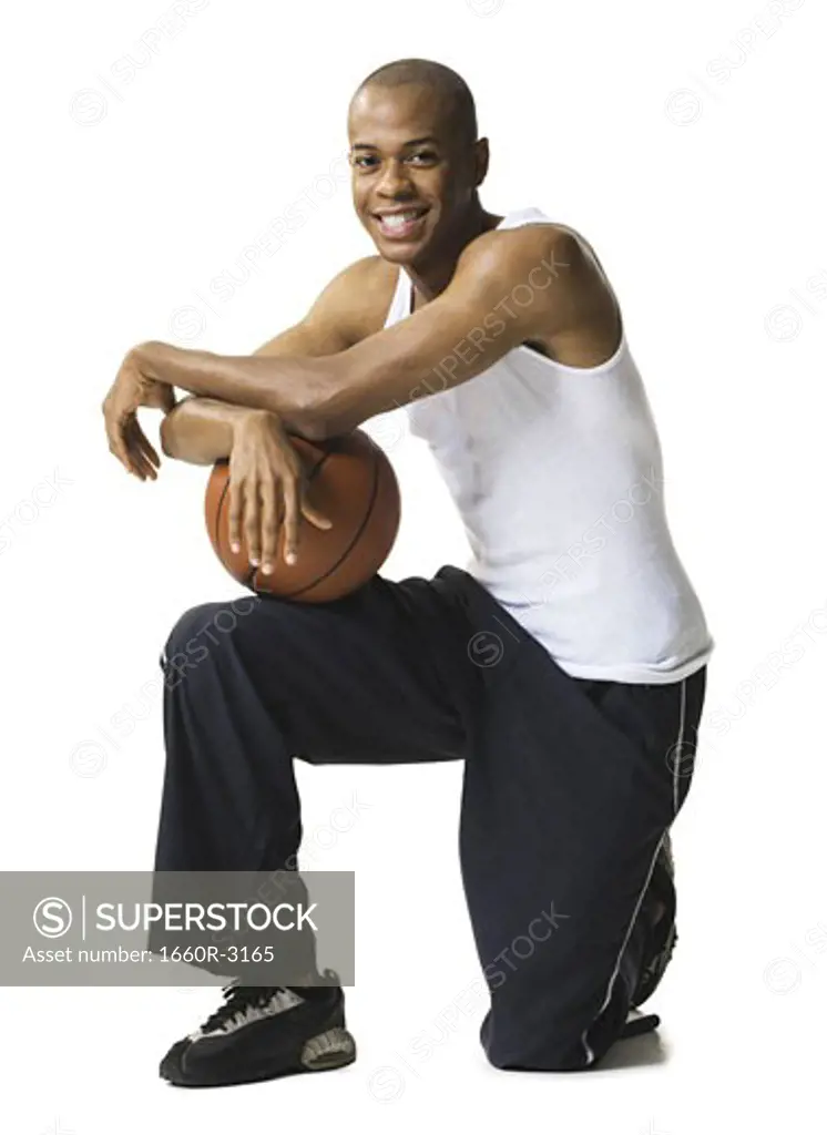 Portrait of a young man kneeling with a basketball