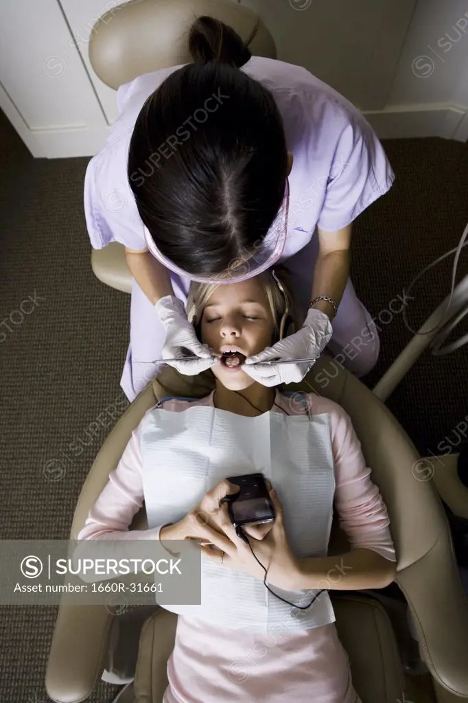 Girl having dental exam with mp3 player