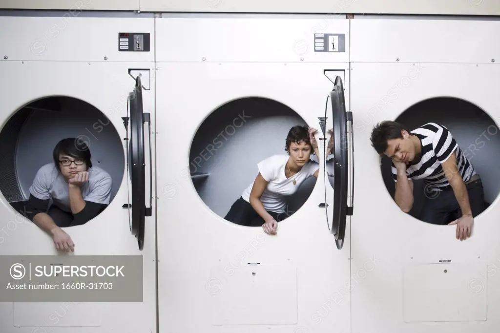 Three people in dryers at Laundromat waiting