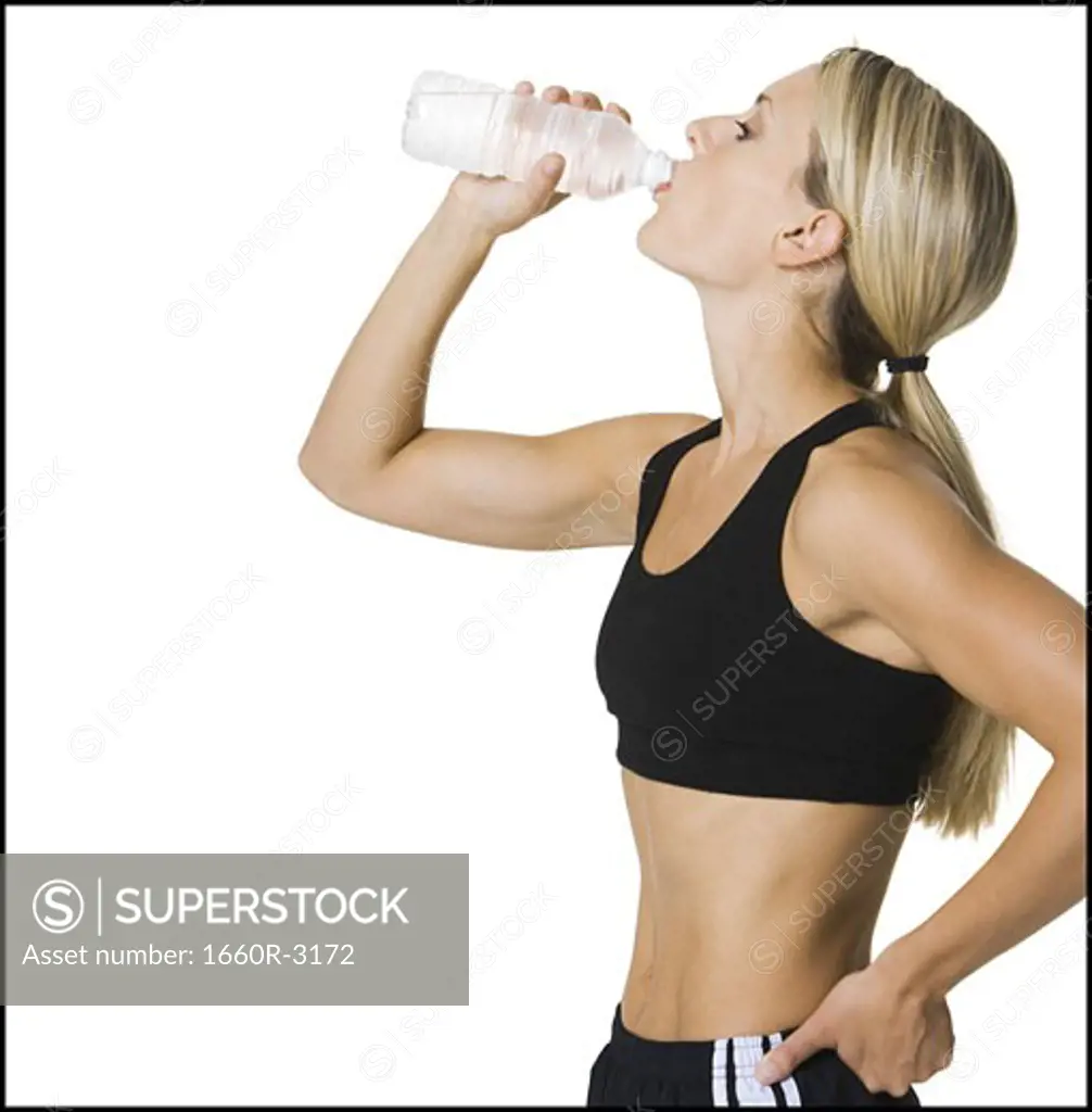 Profile of a young woman drinking water from a bottle