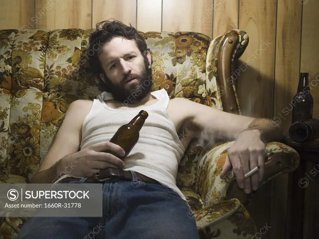Man on couch with beer bottle and cigarette
