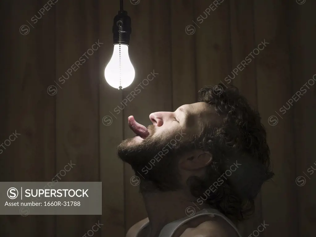 Profile of man with tongue out to light bulb
