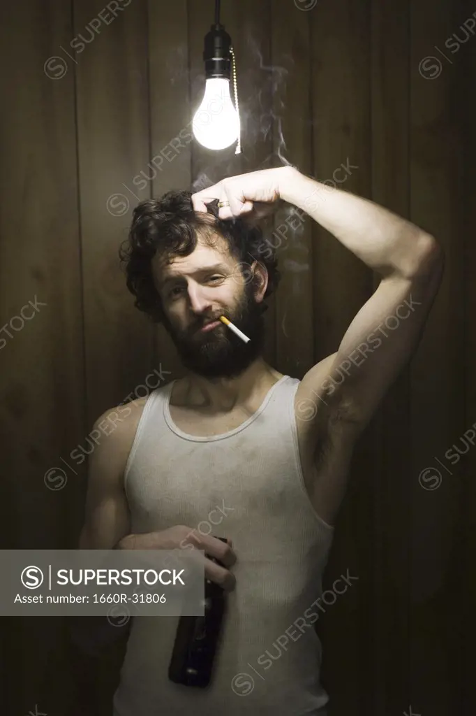 Man standing under light bulb with cigarette and beer bottle