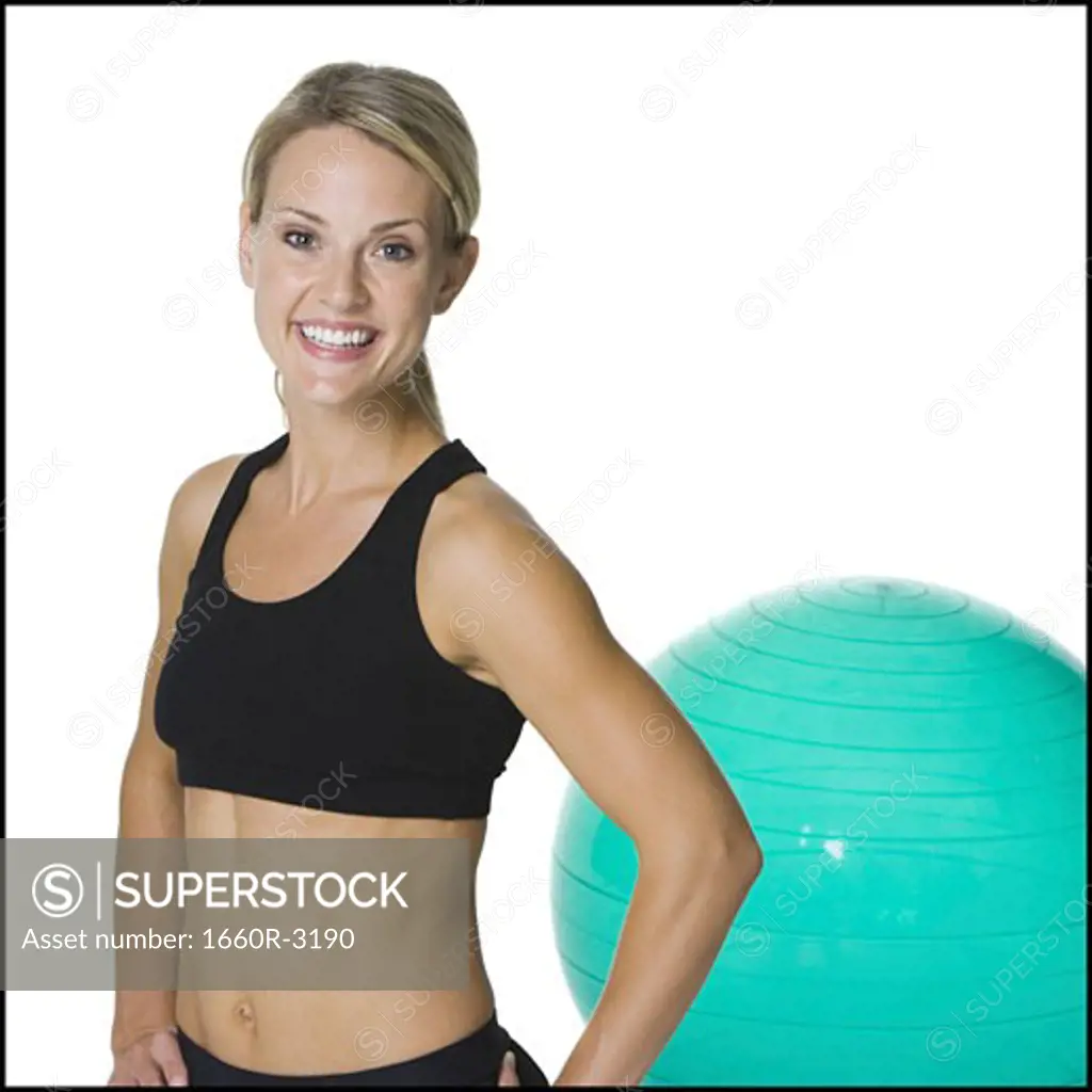 Portrait of a young woman standing in front of an exercise ball
