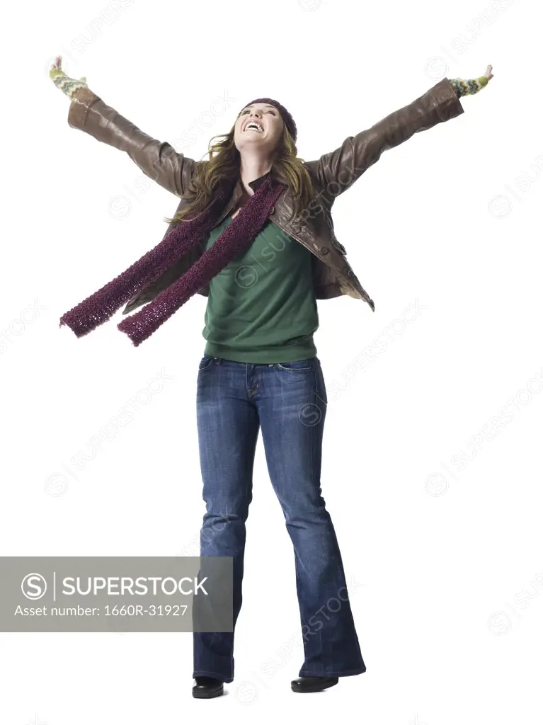 Full length woman with arms raised wearing toque smiling