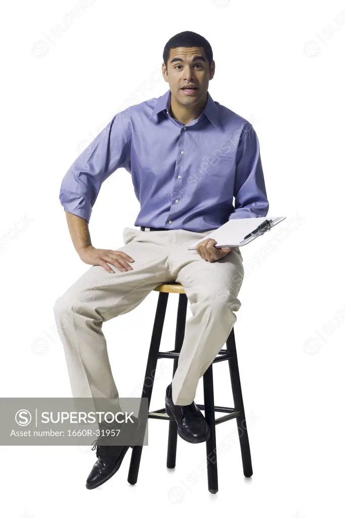 Man sitting on stool with clipboard gesturing