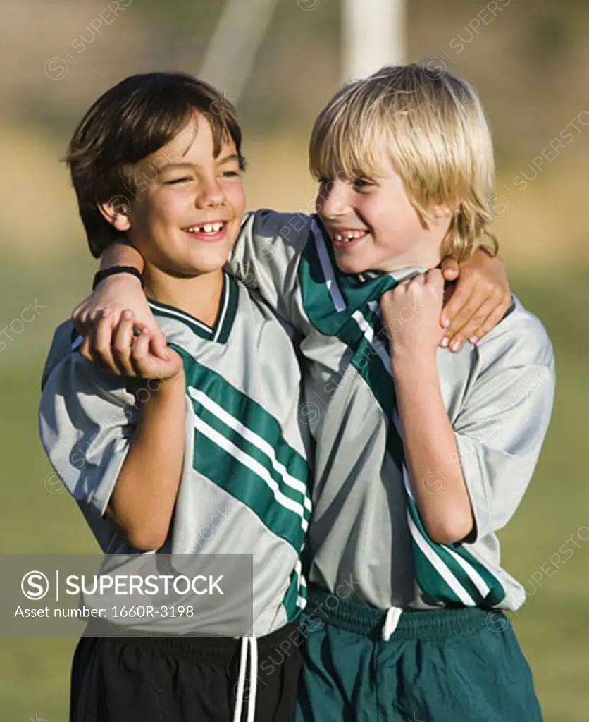 Two boys in soccer uniforms, with arms around each other