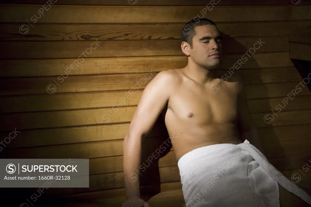Man in sauna with towel relaxing