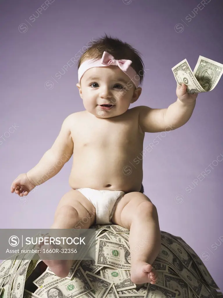Baby girl sitting on pile of US currency