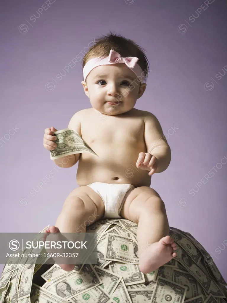 Baby girl sitting on pile of US currency