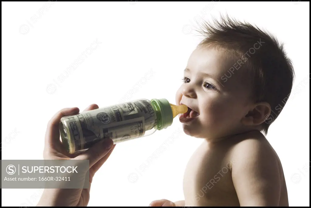 Baby drinking from bottle with US currency in it
