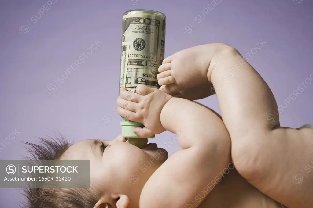 Baby drinking from bottle with US currency in it