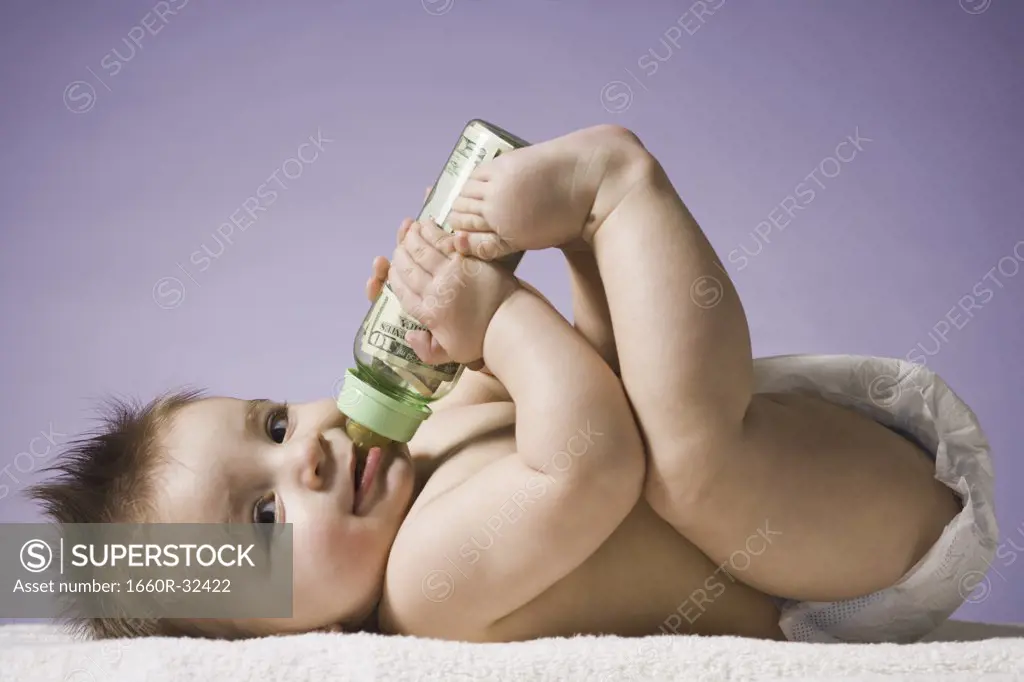 Baby drinking from bottle with US currency in it