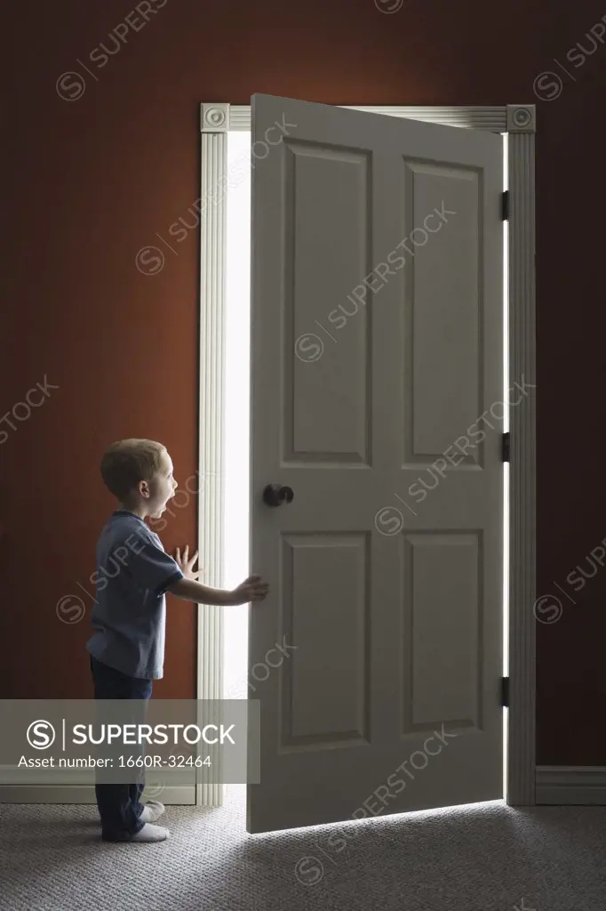 Young boy looking through doorway with mouth open