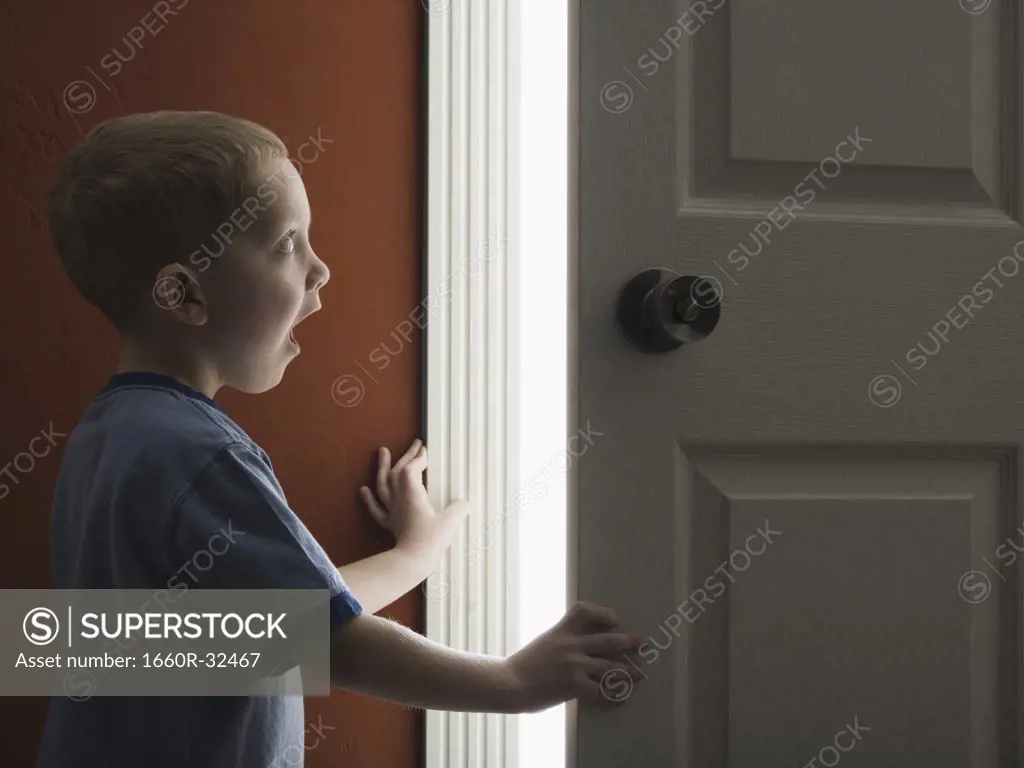 Young boy looking through doorway with mouth open