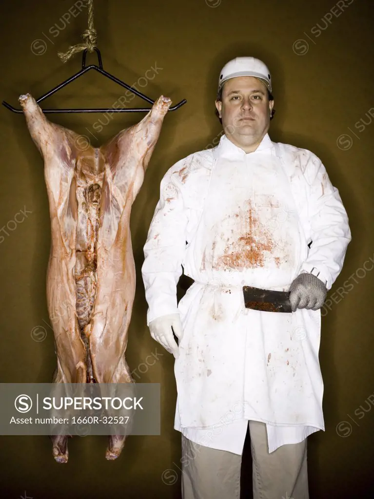 Butcher with hanging carcass and knife smiling