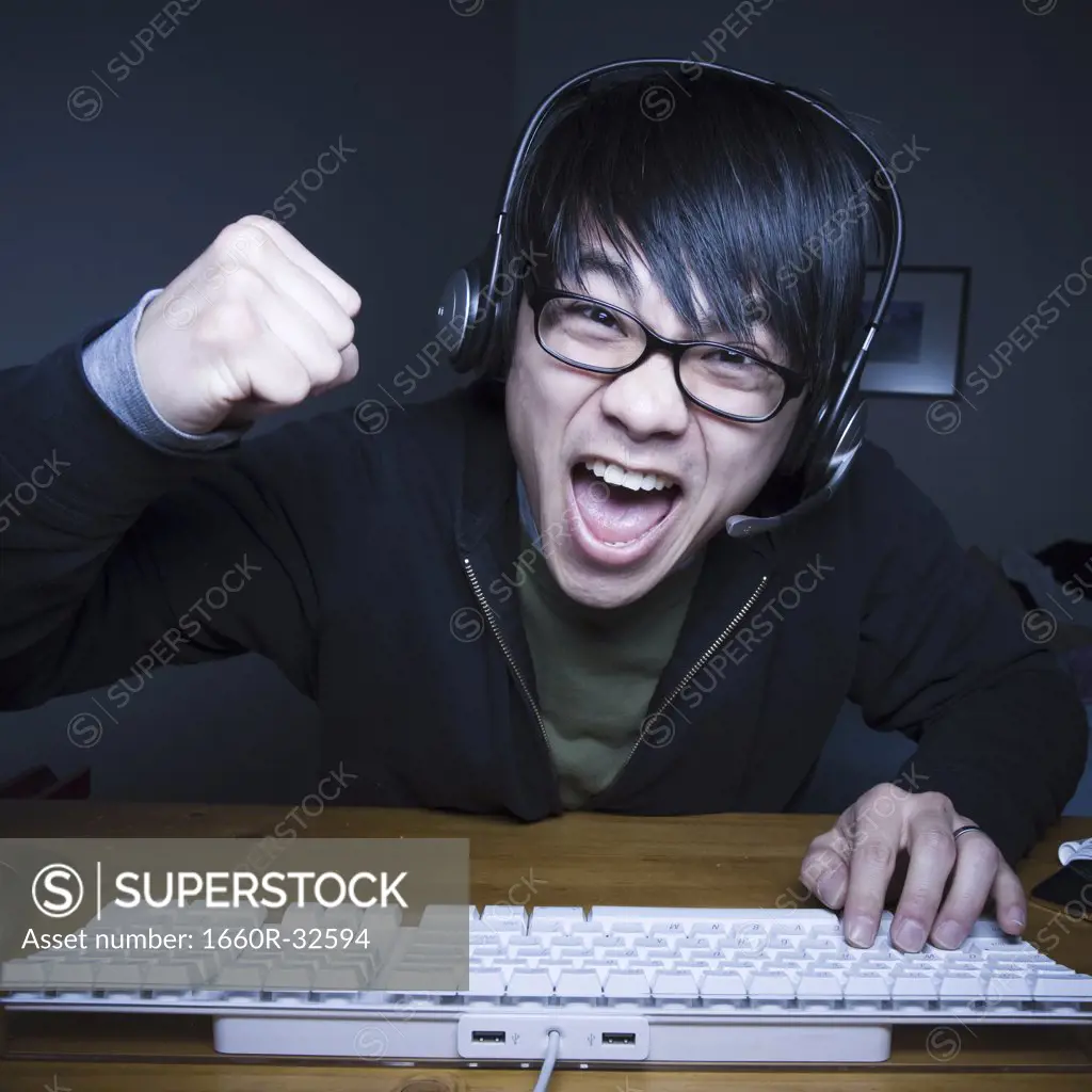 Man with headset making fists and sitting at keyboard
