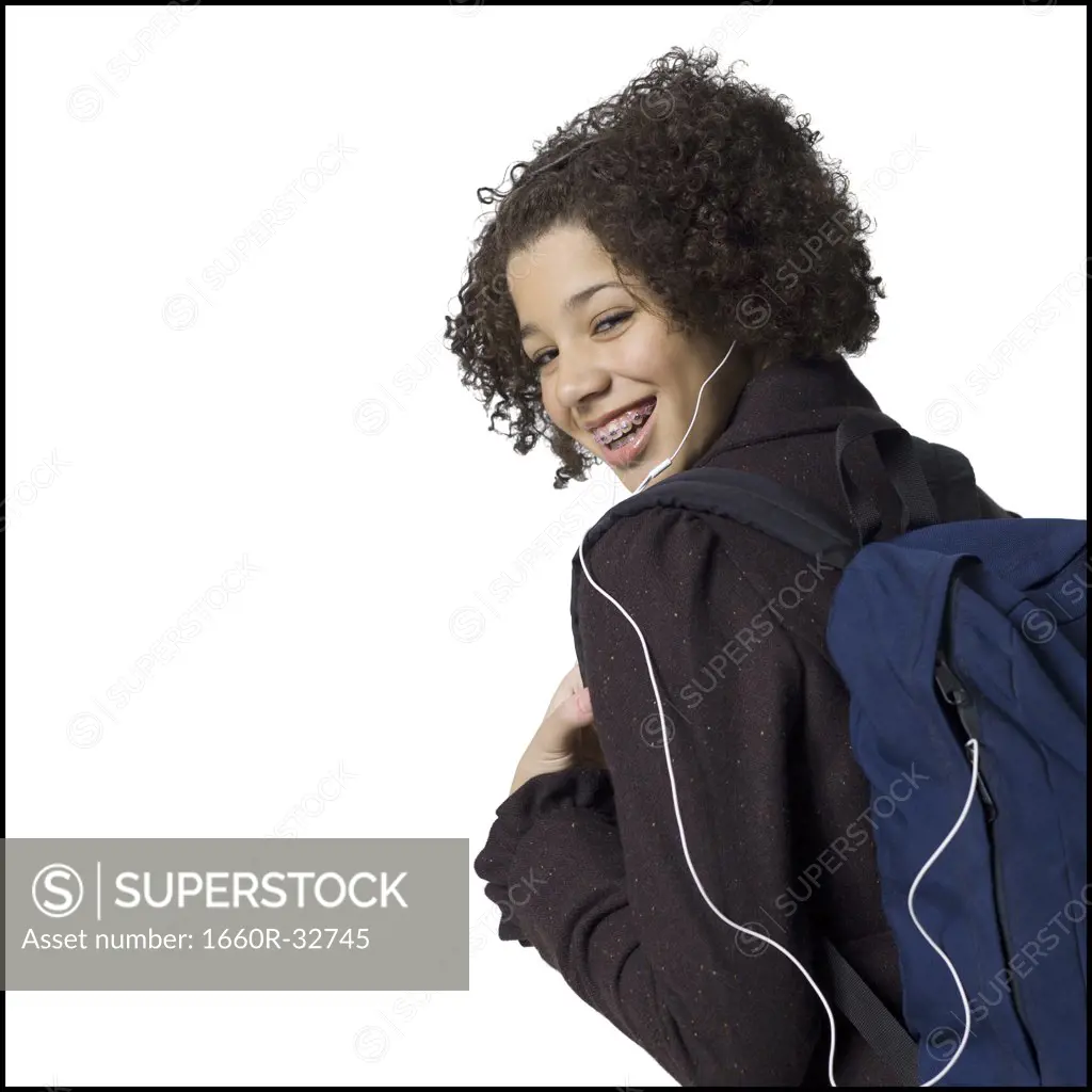 Girl with backpack and earbuds smiling with braces