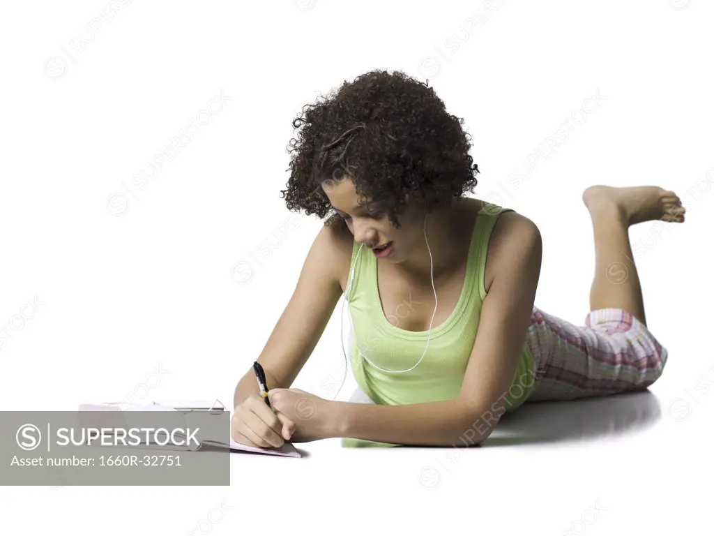 Teenage girl with braces and earbuds writing and smiling