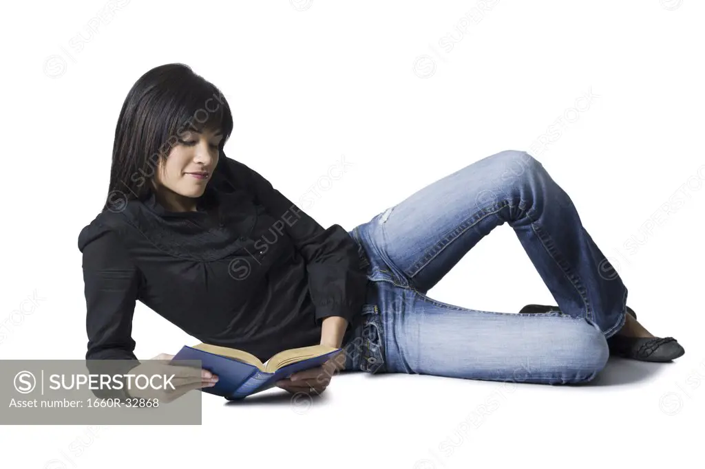 Woman lying down with hardcover book reading
