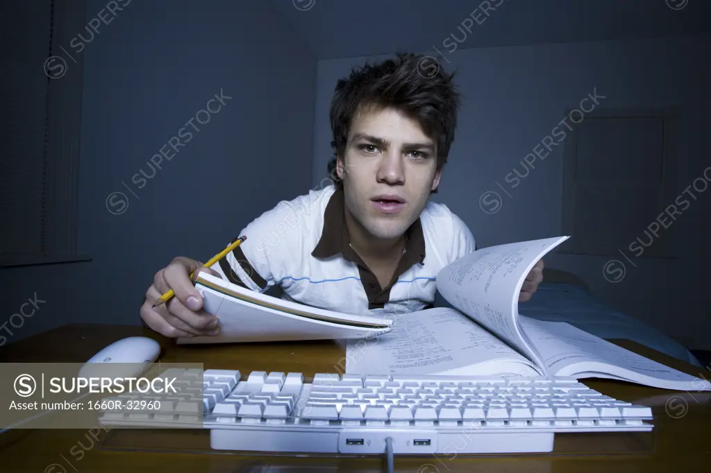 Man at keyboard with pencil and paper taking notes