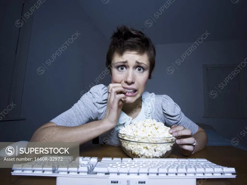 Woman sitting at keyboard with bowl of popcorn
